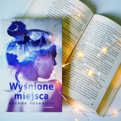 Osoba na okładce książki "Wyśnione miejsca" Brenny Yovanoff, otoczona magicznymi światełkami.