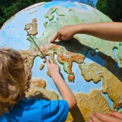 Dziecko i dorosły wskazują na mapę Europy na globusie, ucząc się geografii.