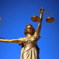 Złota Temida z mieczem i wagą symbolizuje prawo naturalne, które kieruje się sprawiedliwością i obiektywizmem.