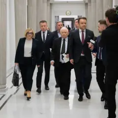Politycy idą korytarzem, a kamerzysta nagrywa ich z tyłu. Widać, że idą w przeciwnych kierunkach, co jest ciekawe.