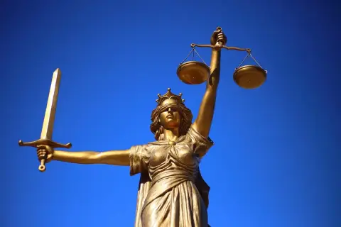Złota Temida z mieczem i wagą symbolizuje prawo naturalne, które kieruje się sprawiedliwością i obiektywizmem.
