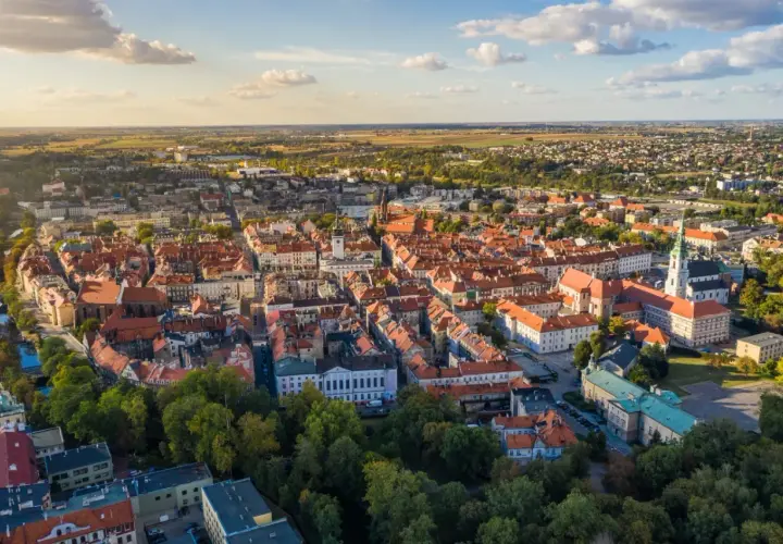 Widok z lotu ptaka na zabytkowe centrum Kalisza, najstarszego miasta w Polsce, z charakterystyczną czerwoną dachówką i zielenią drzew.