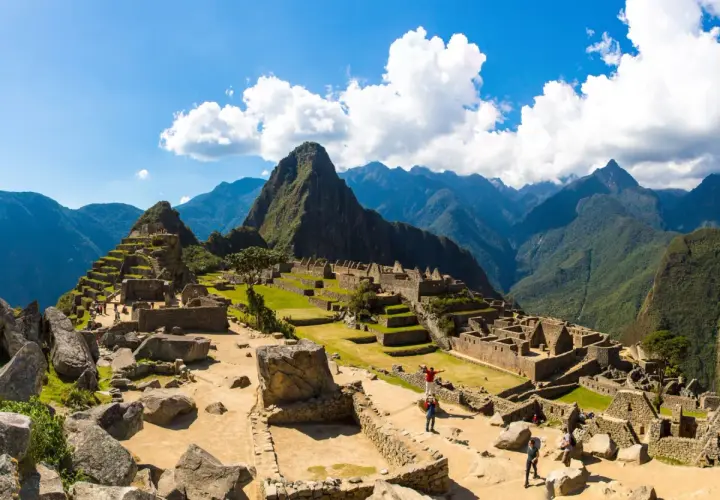 Machu Picchu, dawna twierdza Inków, wznosi się wśród zielonych gór. Turyści zwiedzają ruiny, podziwiając dzieło Inków.
